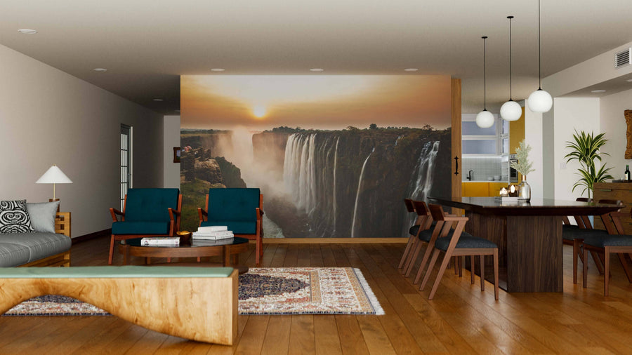 A modern living and dining room features wooden floors, blue armchairs, a natural wood coffee table, and a Victoria Falls Wall Mural at sunset for a peaceful vibe. Round ceiling lights illuminate the wooden dining table with six chairs.