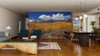 A modern living and dining area with wood floors, teal armchairs, and round pendant lights features the Wasatch Mountain State Park Wall Mural, showcasing golden autumn trees beneath a clear blue sky.