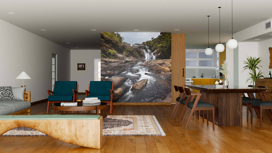 A modern open-plan living and dining room with wooden floors, teal armchairs, a large “Waterfalls in Sri Lanka” Wall Mural, a six-seat dining table, pendant lights, and a yellow-accented kitchen in the background.