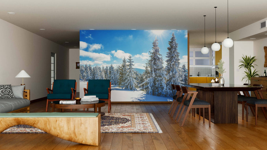 A spacious modern living-dining room features wooden floors, mid-century furniture, and a large Winter Landscape of Snowdrifts Wall Mural showcasing a snowy pine forest under a blue sky, creating a striking contrast with the warm décor.