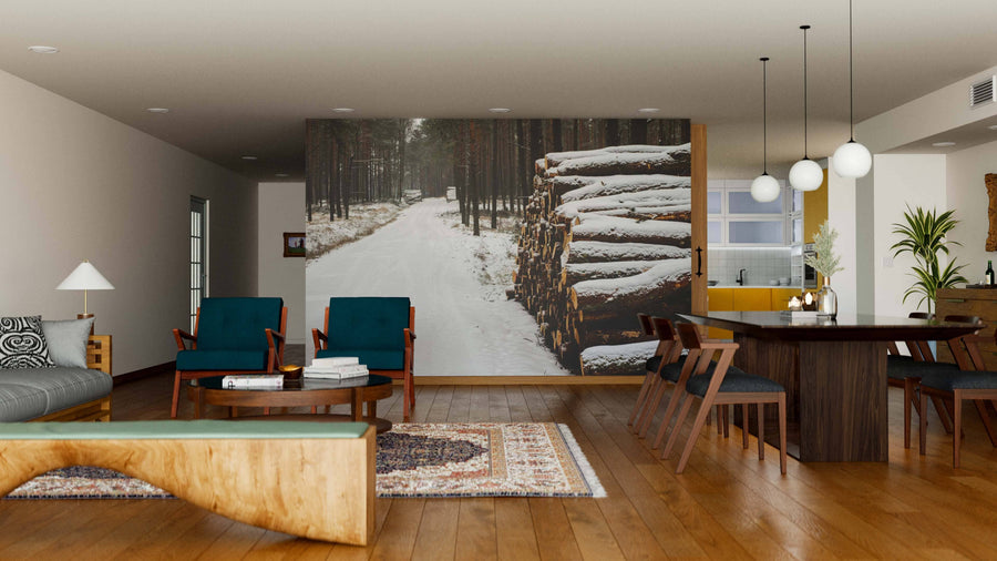 Modern open-plan living and dining space with wood floors, teal chairs, and a dark table. The Wooden Prisms Covered with Snow Wall Mural displays a snowy forest path and logs, bringing wintry outdoor charm indoors.