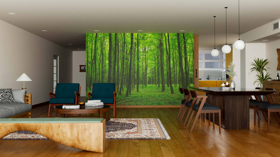 A modern open living-dining room features wood floors, green chairs, a dining table, and the Young Forest Wall Mural as a lush, nature-inspired focal point. Pendant lights hang above the table while natural light fills the space.