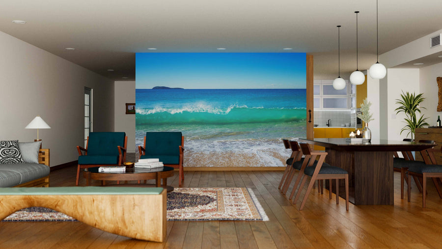 Modern open-concept living-dining room with wood floors and furniture features the Zenith Beach Wall Mural of ocean waves on the back wall, blue chairs, globe pendant lights, a rug, bright atmosphere, and kitchen in view.