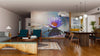 A modern open-plan living and dining area with wood accents features the Lotus Flower With Sun Flare Wall Mural as a vibrant focal point, adding color to neutral tones. Pendant lights illuminate the space above the dining table.