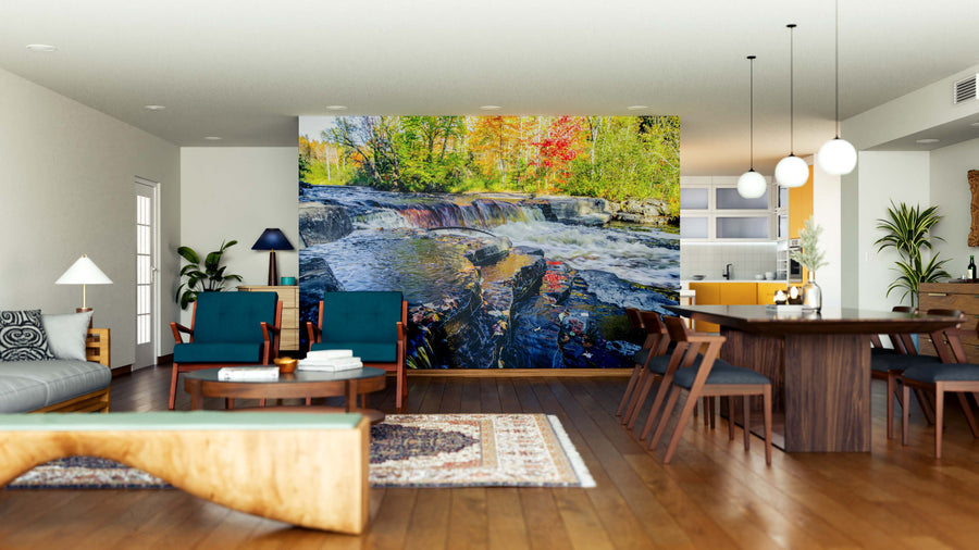 A modern living and dining area with wood floors, mid-century furniture, and a large Michigan Autumn River Wall Mural featuring a vibrant river, waterfall, and autumn trees brings the beauty of nature into the bright, open space.