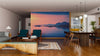 A modern living-dining room features wood floors, green chairs, a wooden dining table, and the Midnight Sun on Water Wall Mural—creating a tranquil, nature-inspired focal point that’s easy to update.
