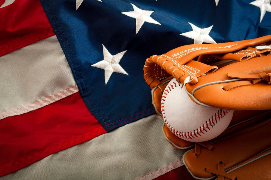 The Baseball and the Flag Wall Mural features a leather glove with a baseball on a crumpled U.S. flag, printed on matte canvas-textured, peel-and-stick material—removable decor that honors American spirit and baseball.
