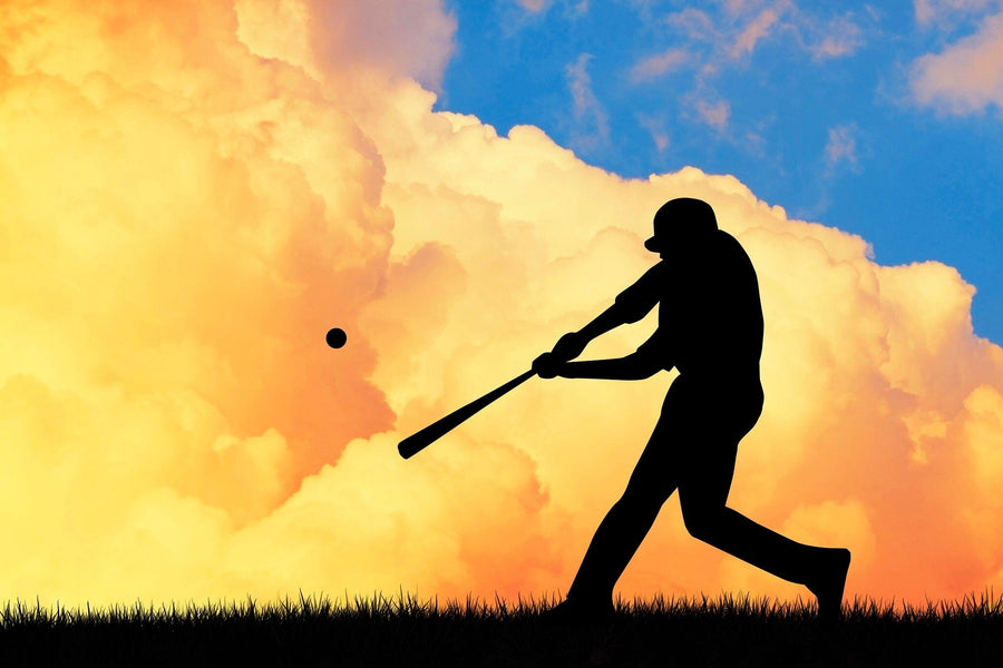 The Batter at Dusk Wall Mural shows a baseball player swinging on grassy ground under bold yellow, orange, and blue clouds—perfect as a vibrant peel and stick wall mural capturing the dramatic moment at dusk.