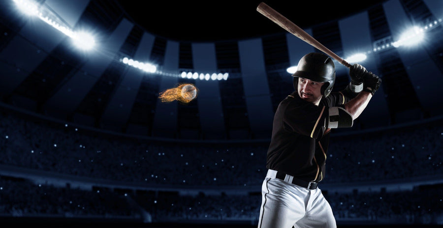 Energize any space with the Blazing Fastball Wall Mural, featuring a dramatic scene of a baseball player in a black uniform and helmet about to swing at a flaming pitch under bright stadium lights. Perfect as an easy peel and stick wall mural.