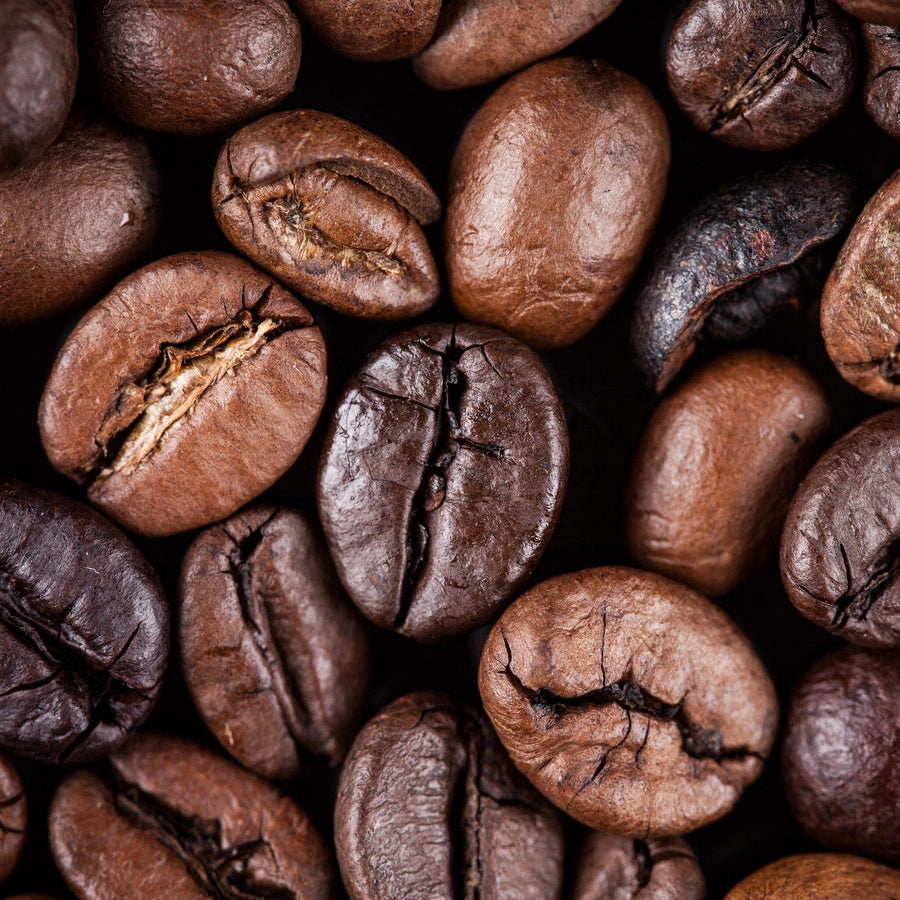 Close-up of roasted coffee beans in varying shades of brown fills the frame like Coffee 12 Wall Mural, with visible cracks and textures highlighting their glossy, slightly oily surfaces, capturing the rich essence akin to a detailed peel and stick design.