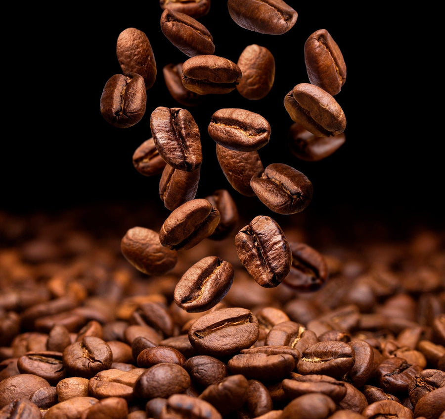 The Coffee Beans Falling Wall Mural features a close-up of glossy, textured coffee beans tumbling in mid-air against a dark background. A rich, aromatic pile forms at the bottom, creating an artful design with various shades of brown reminiscent of removable wallpaper.