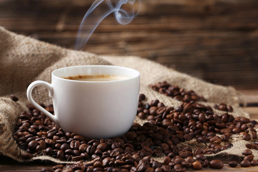 The Coffee Cup on Burlap Wall Mural features a steaming white coffee cup on textured burlap with scattered roasted beans, against a rustic wooden backdrop, enhancing the aromatic ambiance of the scene.