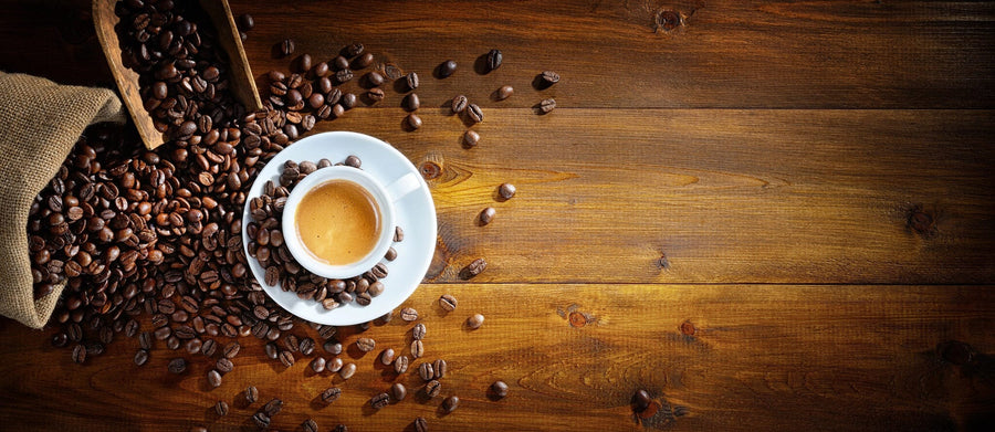 The Espresso and Coffee Beans Wall Mural features a white espresso cup on a saucer with coffee beans on a wooden table, bringing rustic charm and rich brown tones to your space—perfect as a custom printed or peel and stick wall mural.