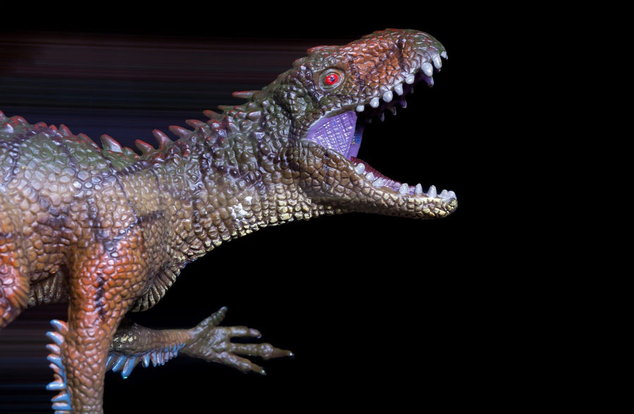 Close-up of a dinosaur figurine against a black background, with textured brown and green scales and an open mouth revealing sharp teeth and a purple tongue. Its red eyes and spiky ridges evoke the Fierce Prehistoric Predator Wall Mural