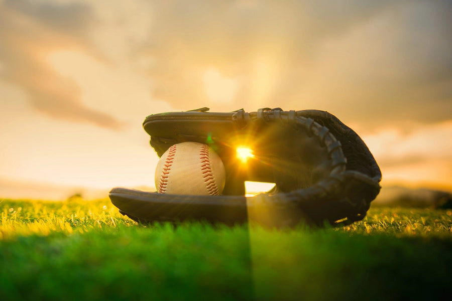 The Golden Hour Catch Wall Mural features a baseball glove and ball on sunlit grass, bathed in a golden sunset glow. This peel and stick mural adds nostalgic charm and peaceful warmth to any space.