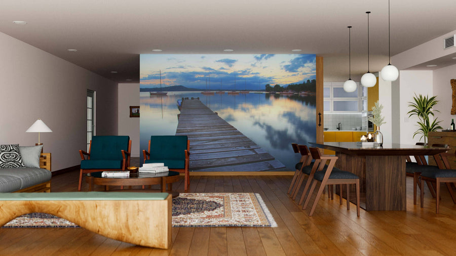 A modern living-dining room with wood floors and stylish furniture features the Mirrored Lake Wall Mural, creating a peaceful vibe. Soft lighting along with contemporary and rustic decor completes the inviting space.