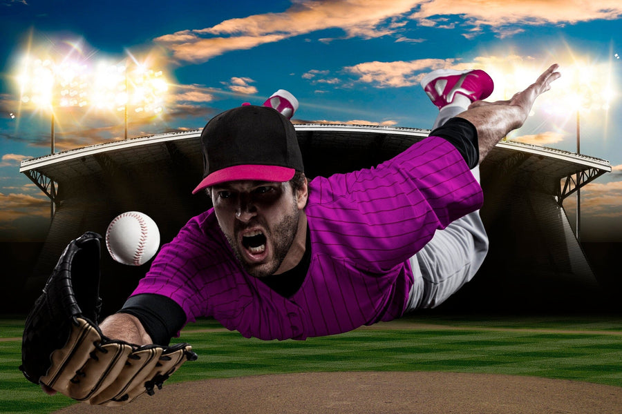 The Professional Baseball Player Wall Mural features a vibrant image of a focused player diving in a pink uniform under stadium lights at dusk—ideal for energizing any room as a wall mural or peel and stick decor.