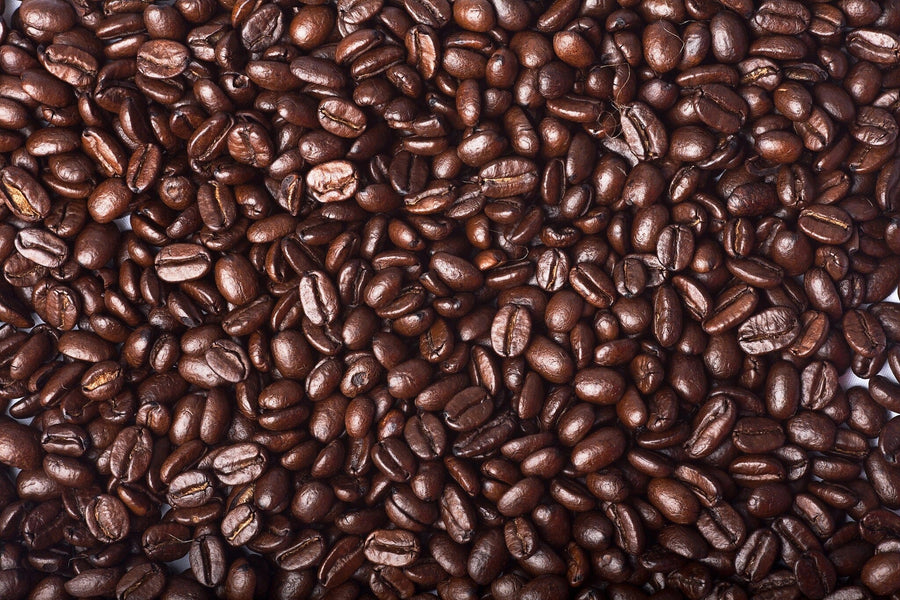 The Rich Coffee Beans Wall Mural by Photo features a detailed close-up of glossy, dark brown beans in varying sizes and shapes, highlighting their natural texture and color against a backdrop similar to peel-and-stick wall murals.