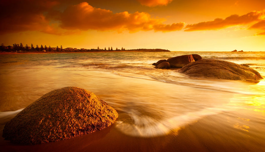 A serene sun tinted beach with rocks and water – Peel and Stick Wall Murals