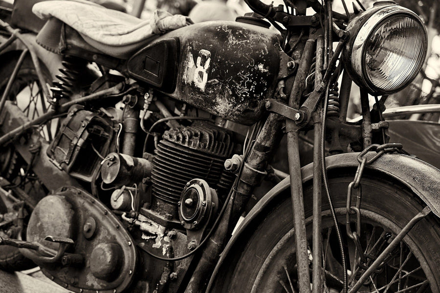 The Vintage Ride Wall Mural features a sepia-toned image of an aged motorcycle with a circular headlight, visible engine parts, and chains. The bike shows wear and rust, boasts a leather seat, and has faded paint on the fuel tank for an authentically vintage look. Perfect for custom murals.