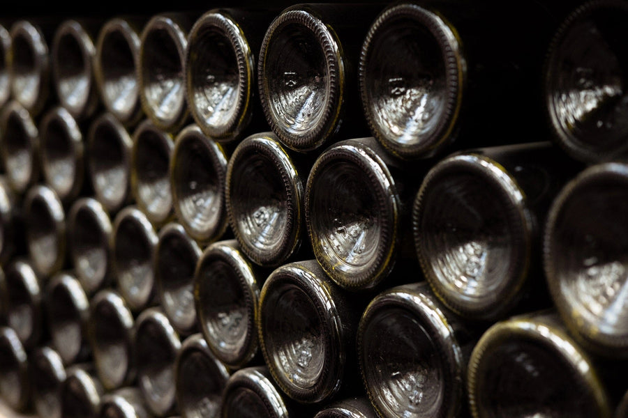 Rows of dark glass wine bottles are depicted on the Wine Bottles Resting Horizontally Wall Mural by, with corked necks facing inward. The lighting adds depth and complements the space with custom printed murals, enhancing the artistic touch to the organized storage area.