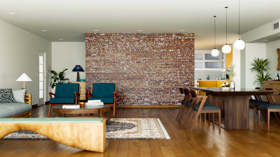 A modern living and dining area features a Mismatched Bricks Wall Mural, blue armchairs, green sofa, round coffee table, wooden dining table for six, pendant lights, rugs, hardwood floors, and a kitchen with white cabinets in the background.