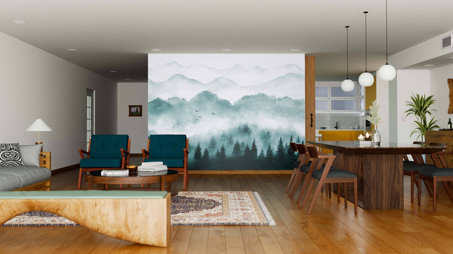 A modern living-dining area with wooden floors, teal armchairs, and a large table features the Misty Green Forest Wall Mural as its centerpiece, creating a serene, nature-inspired atmosphere in the open space.