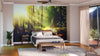 A modern bedroom showcases the Misty Old Forest with Sun Rays Wall Mural behind the bed. Warm wood floors, a ceiling fan, bedside tables, and large glass doors complete the space. The removable mural adds natural beauty with ease.