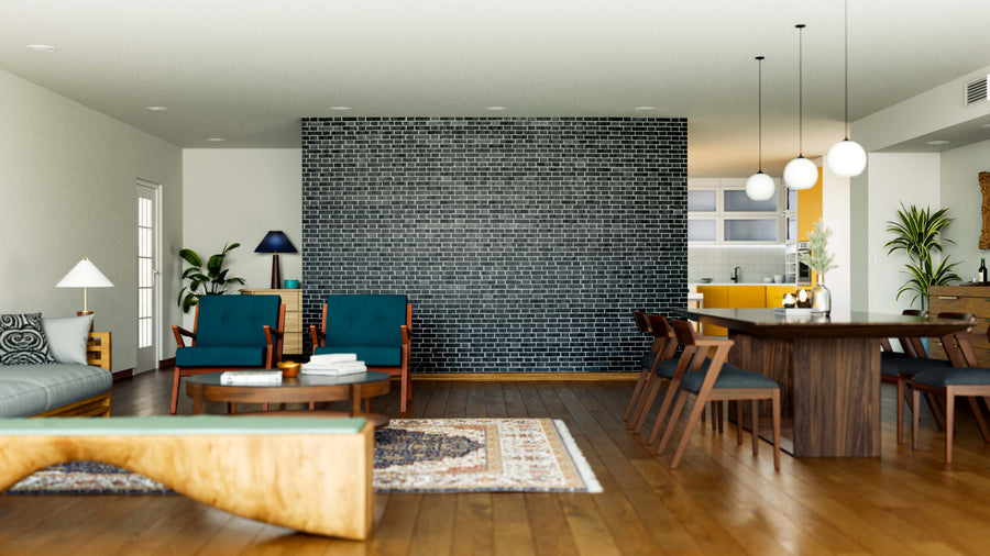 A modern living and dining area features teal armchairs, a gray sofa, a wooden coffee table, and a dark accent wall highlighted by the Monochrome Brick Pattern Wall Mural, with houseplants and an open kitchen with yellow cabinets in the background.
