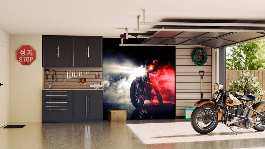 A modern garage with black cabinets, tools on a pegboard, a Korean stop sign, and the Motorcycle in Smoke Wall Mural creates drama. A classic motorcycle stands on the shiny floor near the open door; a green hose hangs on the wall.