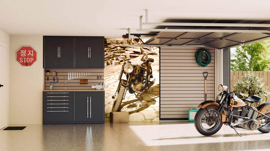 A tidy garage features dark cabinets, neatly hung tools, and a vintage motorcycle. The back wall showcases the Retro Motorcycle in Court Yard Wall Mural, while sunlight streams through the open door.