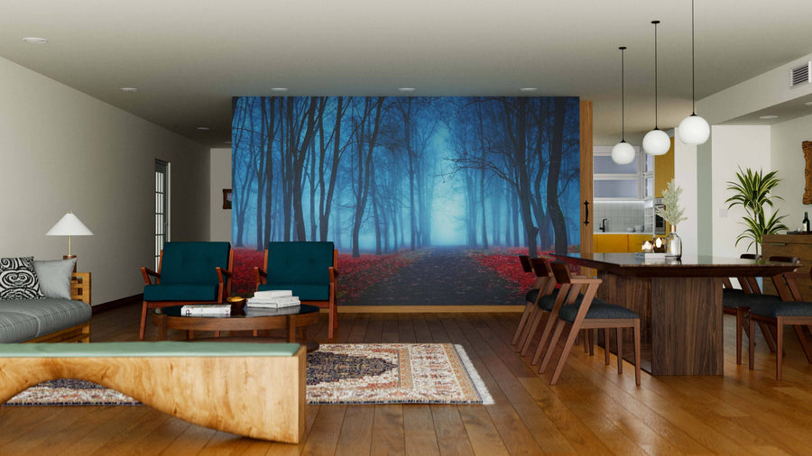 A modern living-dining area with wooden floors and mid-century furniture features the Mystical Forest In Blue Fog Wall Mural, showcasing a misty blue forest with red leaves as a bold focal point in the softly lit, open space.