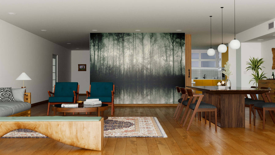 A modern open-plan living and dining area with wood floors, teal chairs, a sectional sofa, and rustic table is divided by the Nebel Wall Mural. Pendant lights shine over the dining table with the kitchen visible nearby.