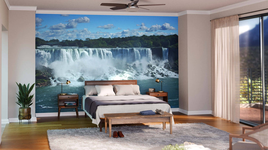 A modern living and dining room with wooden floors and mid-century furniture features the Niagara Falls Wall Mural, adding a scenic waterfall view. Sofas, armchairs, a dining table, and hanging lights complete the space.