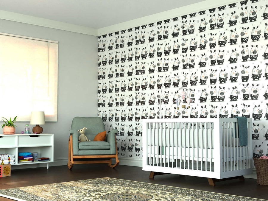 A cozy nursery features the Barnyard Buddies Wall Mural, a white crib, sage green rocking chair with teddy bear, white shelf filled with books and toys, table lamp, large window with shade, and a patterned rug on a dark floor.