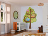 A nursery features a white crib with an orange blanket, basket, toys, and sheer curtains. The Birds and Tree Wall Mural decorates the wall, while a round mirror and pendant light bring warmth to the bright space.