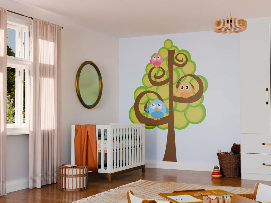 A nursery features a white crib with an orange blanket, basket, toys, and sheer curtains. The Birds and Tree Wall Mural decorates the wall, while a round mirror and pendant light bring warmth to the bright space.