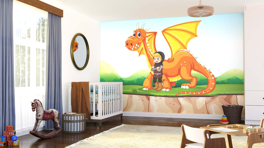A cheerful nursery features a crib, rocking horse, and toys. The Boy and Dragon Wall Mural adds color with a smiling orange dragon, yellow wings, and a happy child in green hills under a bright blue sky.