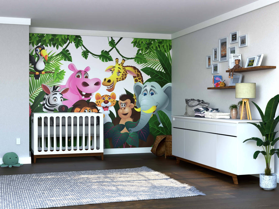 A nursery features a white crib, dresser, green plants, and a light wooden floor. The Cartoon Animals Wall Mural adds cheer with cartoon jungle animals among lush leaves behind the crib, while framed photos complete the space.
