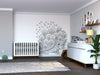 A modern nursery with gray walls features a white crib, a white dresser with a plant, shelves with toys and photos, the Color My Dandy Lions Wall Mural, plus a woven basket and plush turtle on the gray rug.