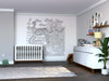 Modern nursery with a white crib, dresser, and plant. The Color My Octopus Wall Mural, featuring an intricate octopus underwater with fish and coral, decorates the wall. Shelf with photos and books above the dresser. Soft natural light fills the room.