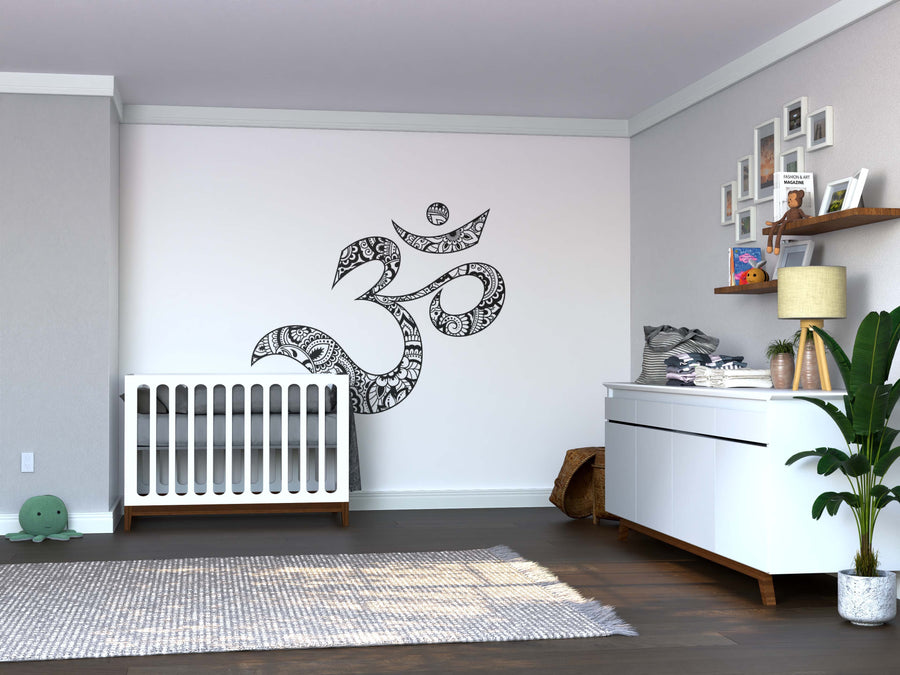 A modern nursery features a white crib and dresser, with wooden shelves for photos. The soft gray wall displays the Color My OM Wall Mural above the crib, on removable wallpaper that makes updating your décor easy.
