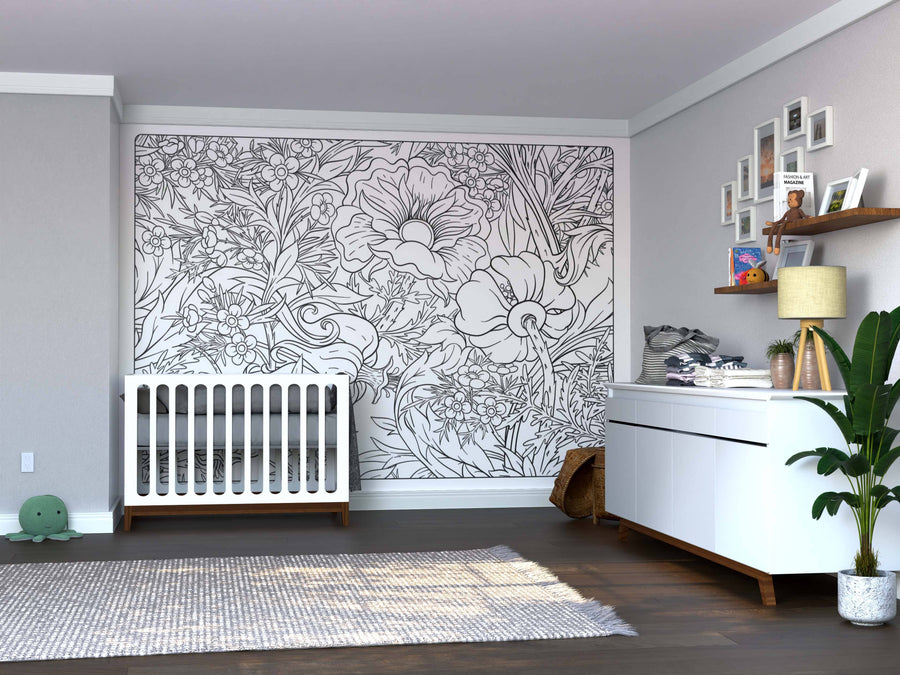 A modern nursery with a white crib, "Color My Secret Garden" wall mural, white dresser with baby supplies, lamp, picture frames, plush turtle, potted plant, and light gray rug on dark wood floors; softly lit and neatly organized.