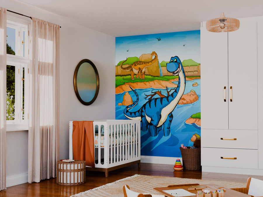A nursery with a crib, toys, and soft furnishings features the Dino Dip Wall Mural: cheerful cartoon dinosaurs by a river amid hills and blue sky. Light filters in through sheer curtains on the window.