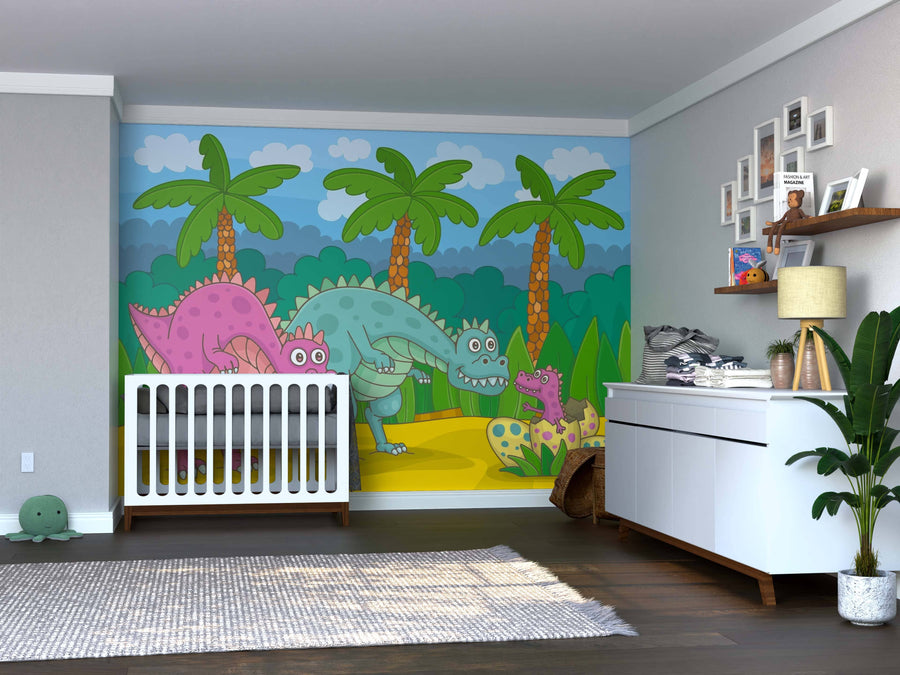 A bright nursery with a white crib, dresser, and plant. The back wall features the Dino Family Wall Mural with cartoon dinosaurs, palm trees, and blue sky. Toys are on the floor; shelves above the dresser hold framed photos and stuffed animals.