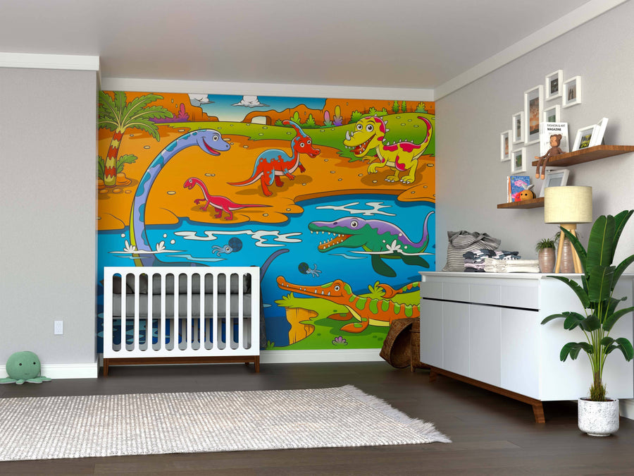 A nursery features the Dinosaur Lagoon Wall Mural, showcasing cartoon dinosaurs and prehistoric creatures by water and palm trees. The room includes a white crib, modern dresser, toy shelves, framed photos, a leafy plant, and wooden floors.