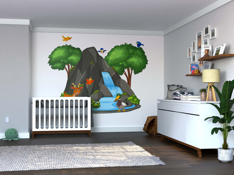 A nursery with a white crib, dresser, green plant, and the Forest Waterfall Scene Wall Mural showing a waterfall, trees, and cartoon animals like birds, a fox, and a duck. Baby supplies and pictures sit on the dresser and wall shelves.