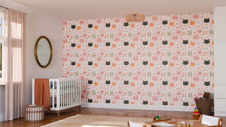 A nursery with a crib, mirror, and toys features a playful accent wall covered in the Furry Friends Wall Mural, adorned with cartoon cat faces in pink, orange, and black. Sunlight through sheer curtains creates a bright, cozy atmosphere.