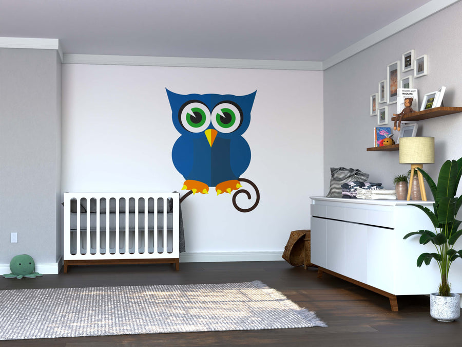 A modern nursery with a white crib and dresser, light gray walls, dark wood floor, and a Geometric Blue Owl Wall Mural. Shelves with toys, a potted plant, framed photos, and a gray rug complete the cozy decor.