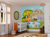 A nursery features a white crib, orange blanket, wicker stool, and the Lush Safari Scene Wall Mural with cartoon giraffe, zebra, deer, and rhino by a pond. Light filters through sheer curtains and a round mirror decorates the wall.